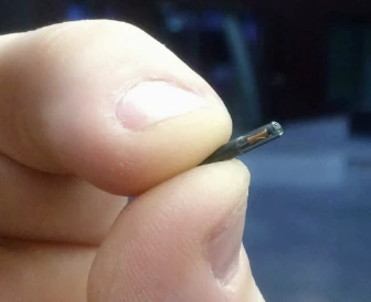 Close-up of a human hand with a visible subdermal NFC microchip implant under the skin showing the bioglass encapsulation Close-up of a human hand with a visible subdermal NFC microchip implant under the skin showing the bioglass encapsulation
